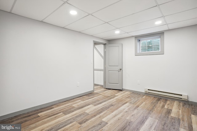 unfurnished room featuring a baseboard radiator, a paneled ceiling, and light wood-type flooring