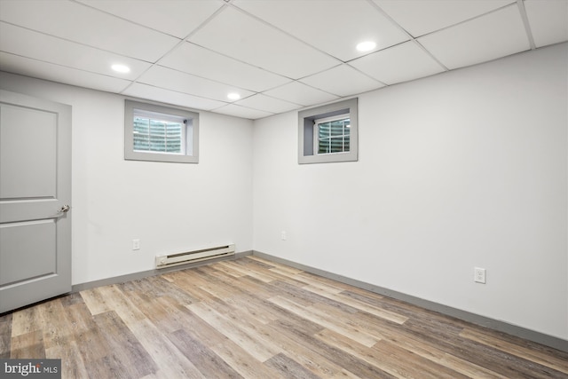 basement featuring a paneled ceiling, light hardwood / wood-style flooring, and a baseboard radiator