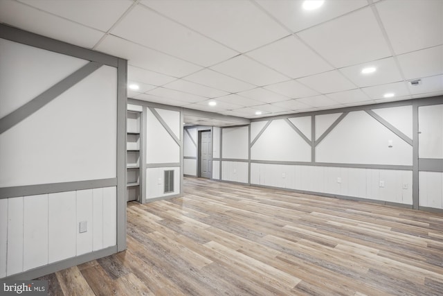 basement with a paneled ceiling and hardwood / wood-style flooring