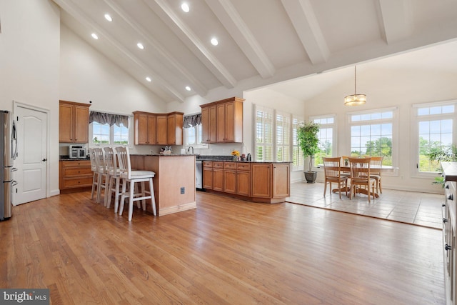 kitchen featuring appliances with stainless steel finishes, a breakfast bar, pendant lighting, a high ceiling, and plenty of natural light