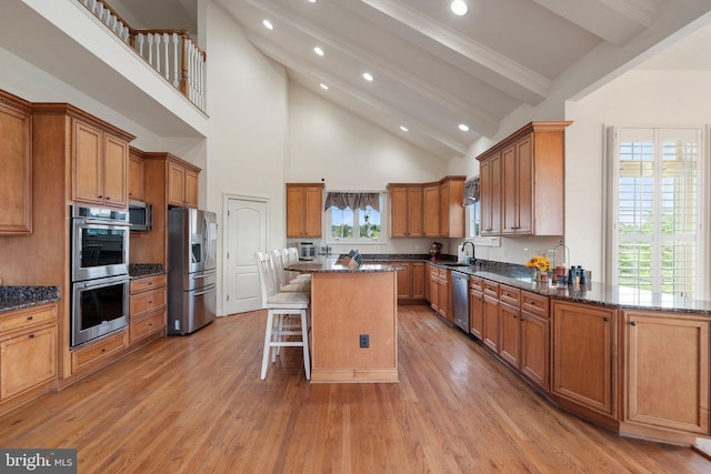 kitchen with a kitchen island, beamed ceiling, sink, a kitchen breakfast bar, and stainless steel appliances