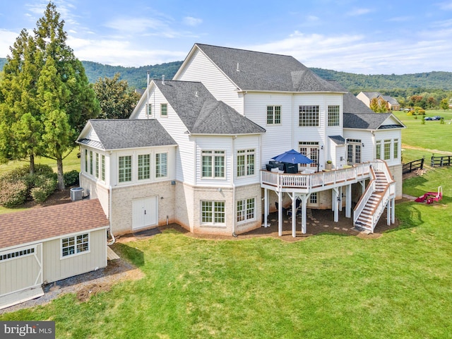 rear view of house featuring a shed, a yard, central air condition unit, and a deck