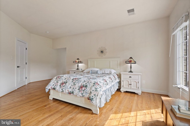 bedroom with multiple windows and light hardwood / wood-style flooring