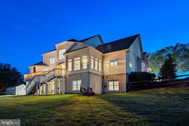 property exterior at dusk featuring a yard, a deck, and a storage unit