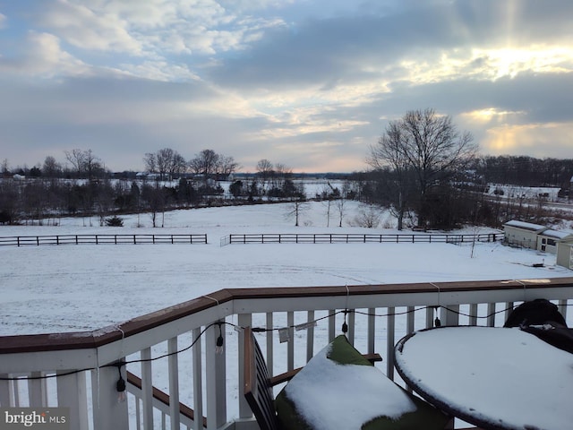 snow covered deck with a rural view