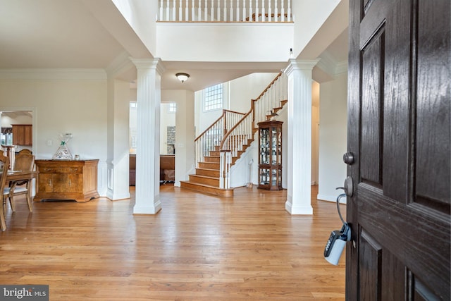 entrance foyer with crown molding, light hardwood / wood-style flooring, and ornate columns