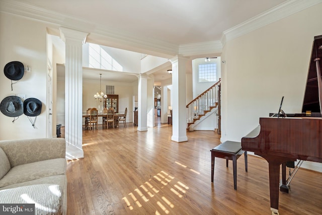 interior space featuring hardwood / wood-style flooring, ornamental molding, a chandelier, and ornate columns