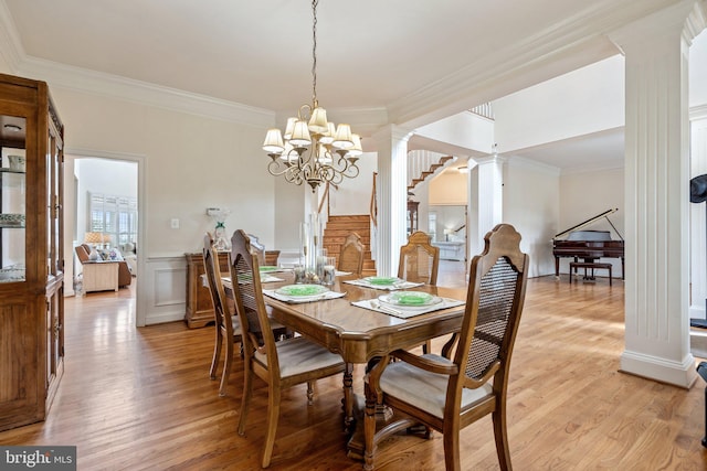 dining room with crown molding, an inviting chandelier, light hardwood / wood-style flooring, and ornate columns