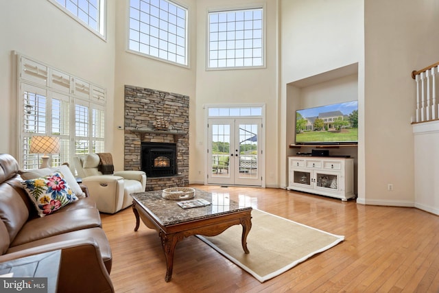 living room with light wood-type flooring, plenty of natural light, french doors, and a high ceiling