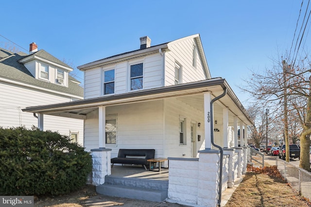 view of front of house featuring covered porch, a fenced front yard, and a chimney