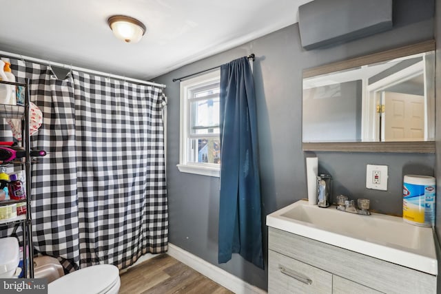 full bathroom featuring toilet, a shower with shower curtain, wood finished floors, vanity, and baseboards