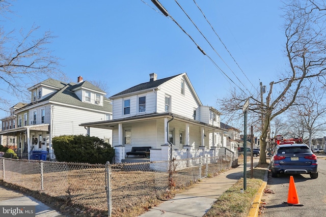 view of side of property with a porch and a fenced front yard