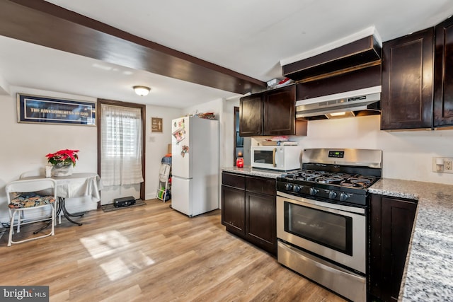 kitchen featuring dark brown cabinets, light stone countertops, light wood-type flooring, white appliances, and under cabinet range hood