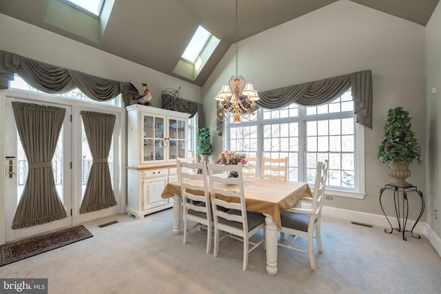 carpeted dining space with vaulted ceiling with skylight and a notable chandelier