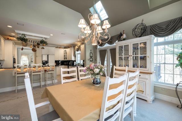 tiled dining room featuring a chandelier and a skylight