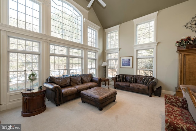 carpeted living room featuring ceiling fan and a towering ceiling