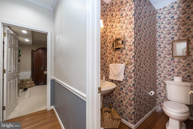 bathroom featuring hardwood / wood-style flooring, toilet, and crown molding