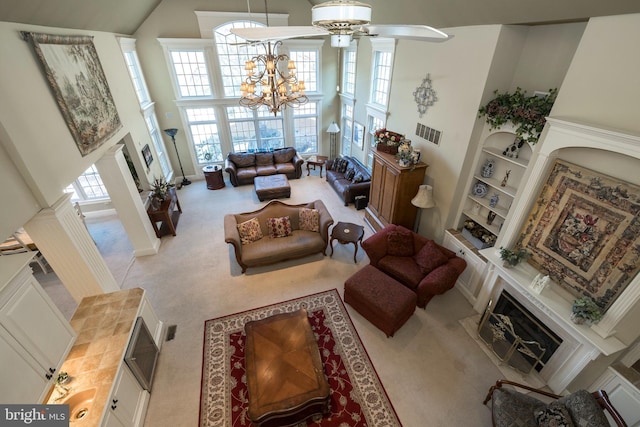 living room featuring built in shelves, a towering ceiling, light carpet, and an inviting chandelier