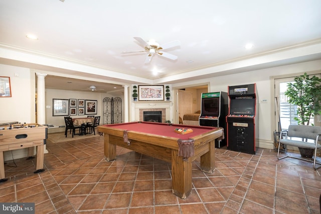 playroom with ornate columns, ceiling fan, billiards, a tiled fireplace, and ornamental molding