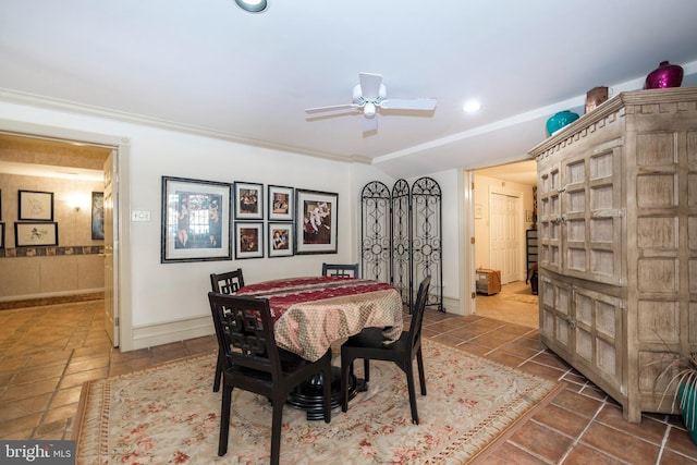 tiled dining area with ceiling fan and ornamental molding