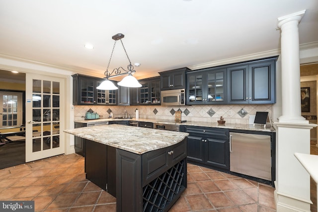 kitchen with a center island, hanging light fixtures, ornate columns, appliances with stainless steel finishes, and tasteful backsplash