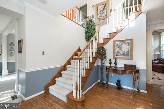 stairway with wood-type flooring and ornamental molding