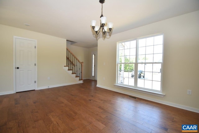 spare room with a chandelier and dark wood-type flooring