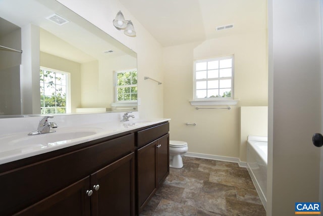 bathroom with vanity, toilet, and a tub