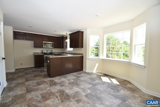 kitchen featuring decorative light fixtures, dark brown cabinets, sink, and appliances with stainless steel finishes