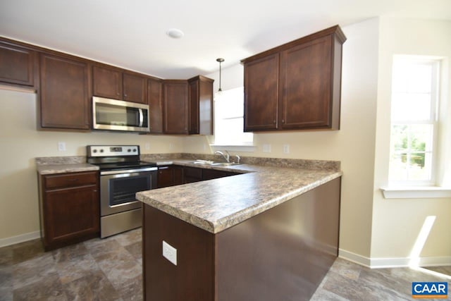 kitchen featuring kitchen peninsula, dark brown cabinetry, stainless steel appliances, sink, and decorative light fixtures