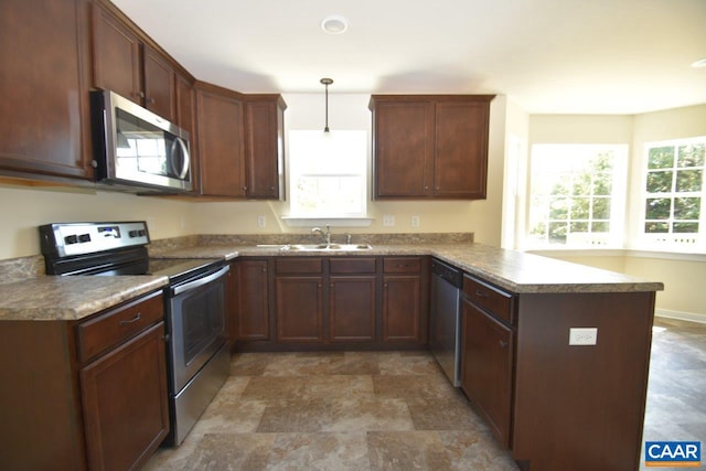 kitchen featuring kitchen peninsula, sink, stainless steel appliances, and decorative light fixtures