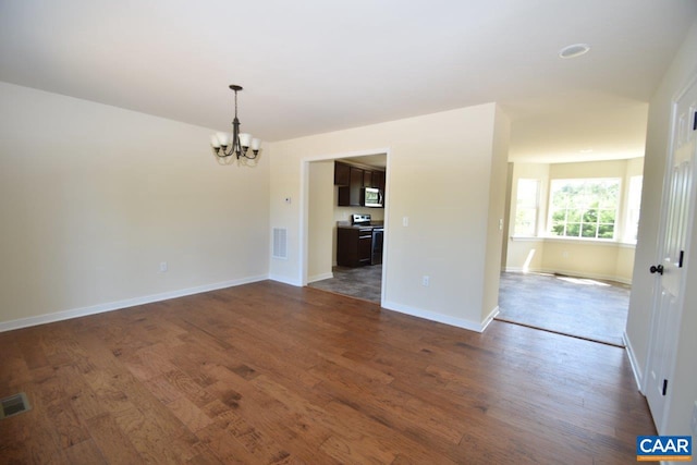 spare room with dark hardwood / wood-style floors and a notable chandelier