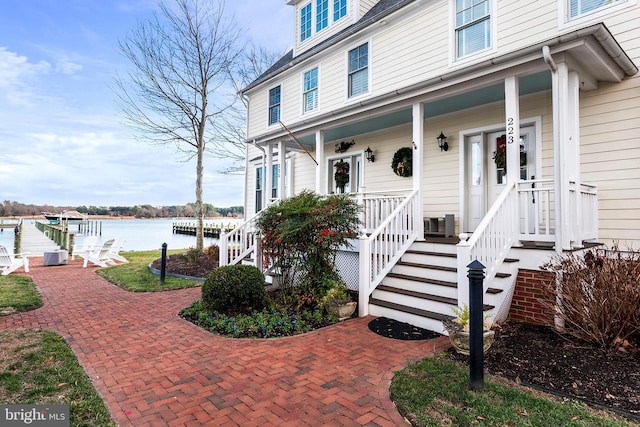 view of exterior entry with covered porch and a water view