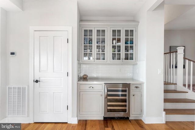 bar featuring light hardwood / wood-style floors, wine cooler, and tasteful backsplash