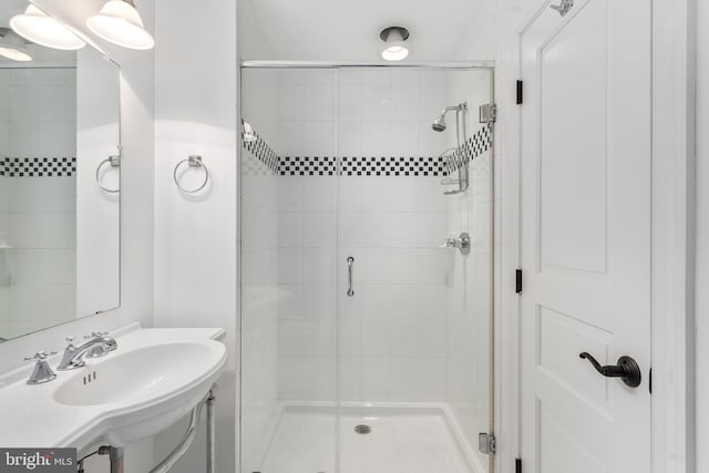 bathroom with a shower with door and sink