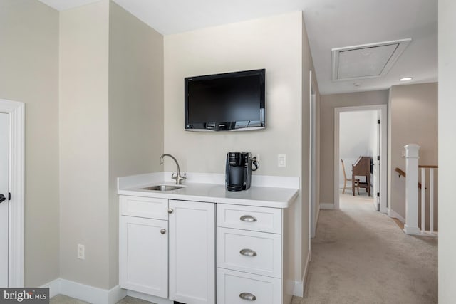 bar featuring white cabinetry, sink, and light carpet