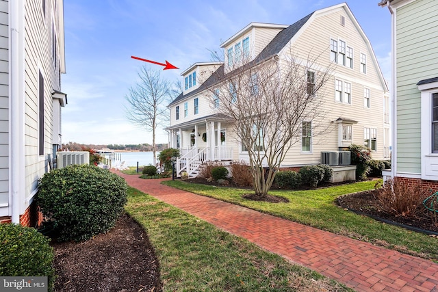 view of front of property with cooling unit, a porch, a water view, and a front yard