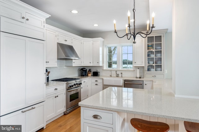 kitchen with a kitchen bar, white cabinetry, hanging light fixtures, and high quality appliances