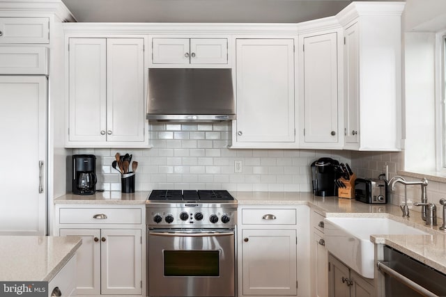 kitchen featuring wall chimney exhaust hood, premium appliances, decorative backsplash, and white cabinetry