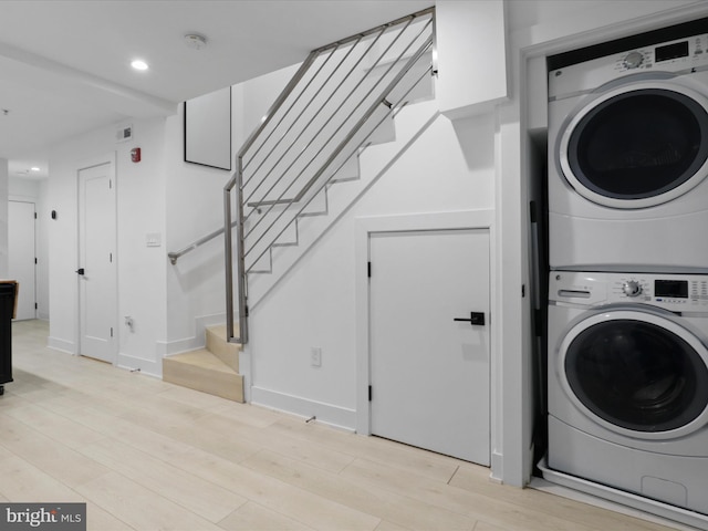 washroom featuring light hardwood / wood-style floors and stacked washer / drying machine