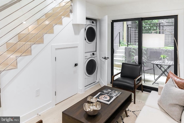 laundry room with light hardwood / wood-style floors and stacked washer and clothes dryer