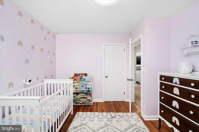 bedroom featuring dark hardwood / wood-style flooring and a nursery area