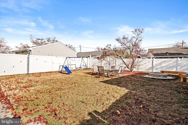 view of yard featuring a playground and an outdoor fire pit