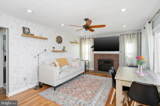 living room featuring a fireplace, hardwood / wood-style floors, and ceiling fan