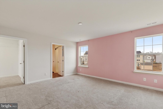 unfurnished bedroom with a spacious closet and light colored carpet