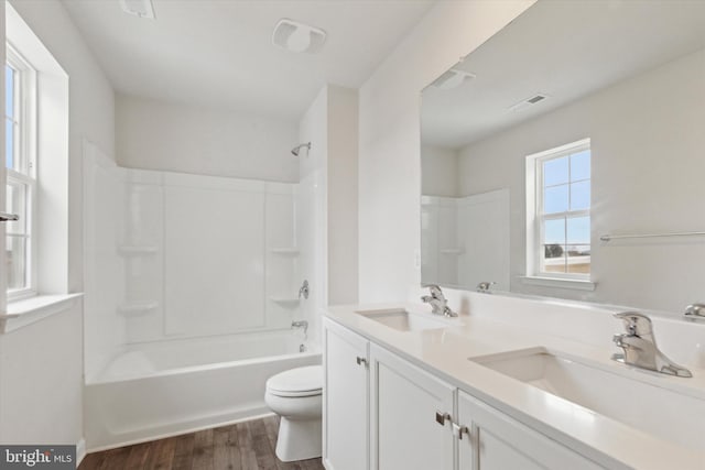 full bathroom with shower / bath combination, vanity, hardwood / wood-style floors, and toilet