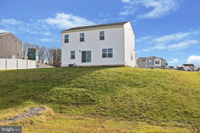 rear view of house featuring central AC and a lawn