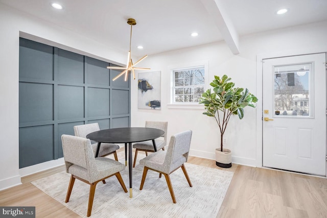 dining area featuring beamed ceiling, a notable chandelier, and light hardwood / wood-style floors