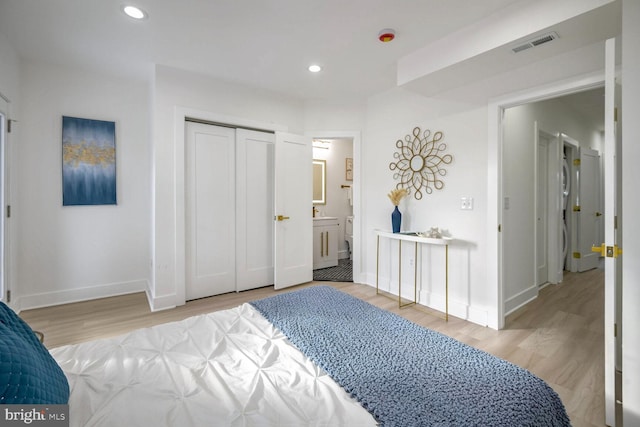 bedroom featuring connected bathroom and light hardwood / wood-style flooring