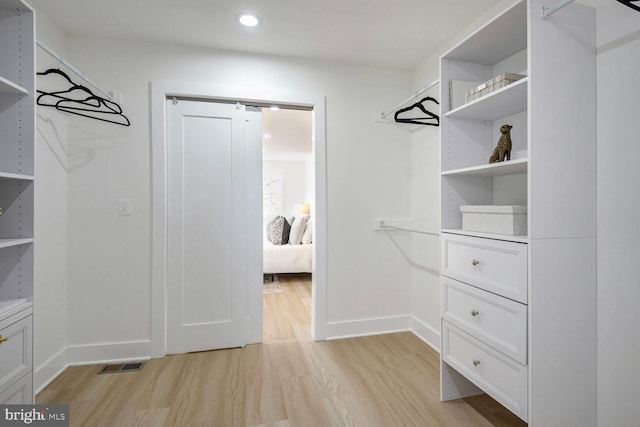 spacious closet with a barn door and light hardwood / wood-style flooring